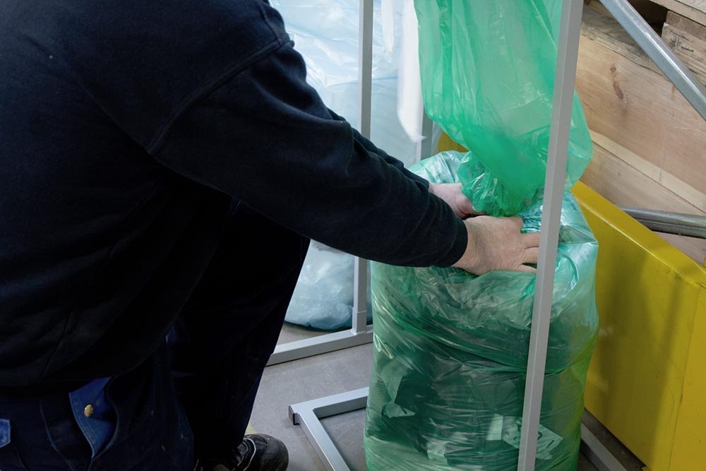 Mitarbeiter verschließt einen grünen Infinity-Abfallsack